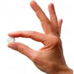 holding weight loss tablet with two fingers